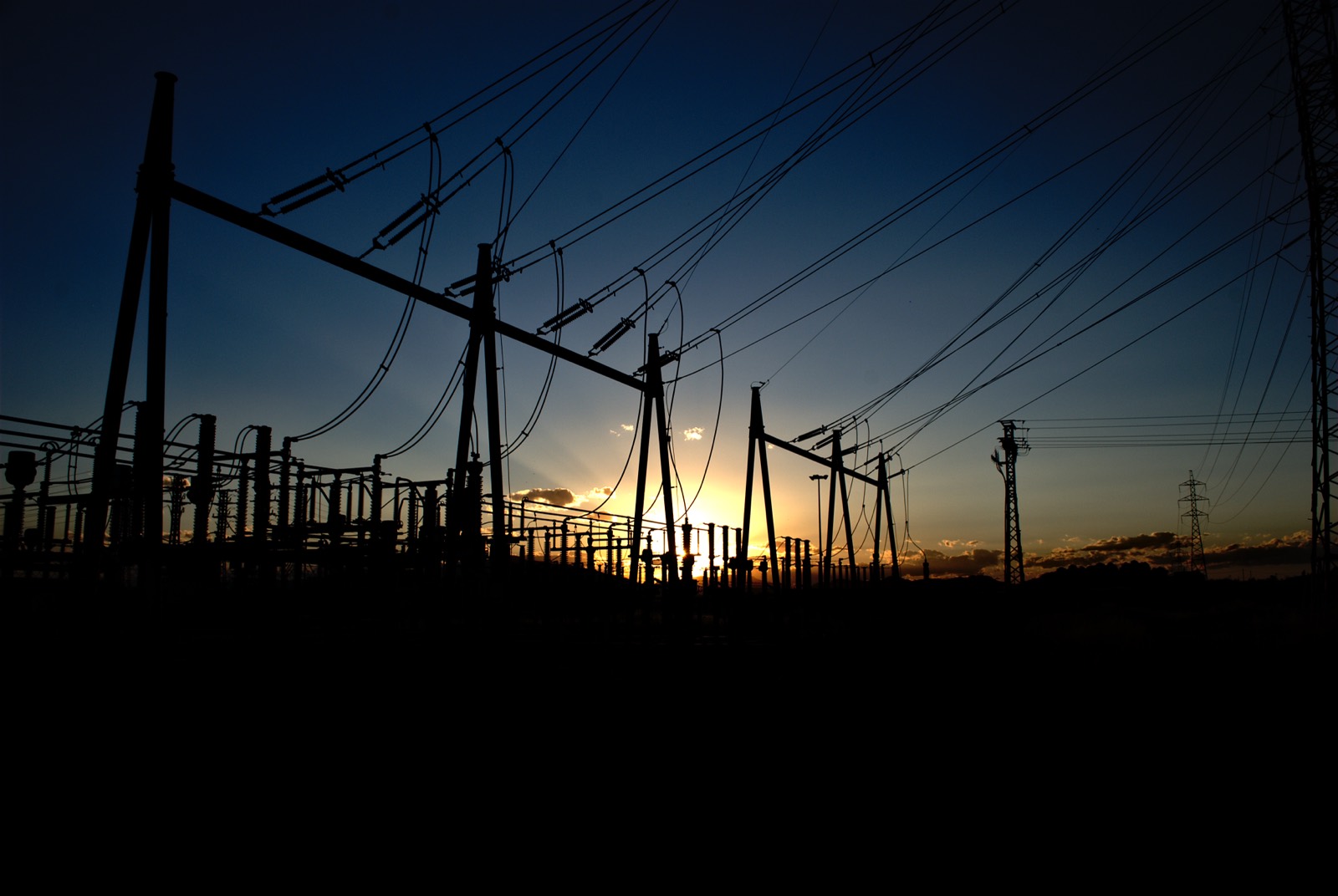 A high-voltage electrical substation silhouetted at sunset